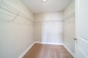 Thumbnail 15 of 22 - Walk in closet with white wire shelving, plush carpeting, and cream walls.