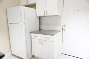 Thumbnail 28 of 38 - a small kitchen with white cabinets and a white refrigerator