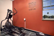 Thumbnail 34 of 48 - a gym with an exercise bike and a sign that says pain is temporary quitting lasts forever