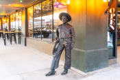 Thumbnail 41 of 84 - a statue of a man in a cowboy hat standing on a sidewalk