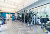 Thumbnail 36 of 55 - a gym with cardio machines and weights in a building with large windows