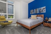 Thumbnail 9 of 24 - a bedroom with a blue accent wall and a bed with a wooden headboard at Napoleon Apartments, Tacoma, WA