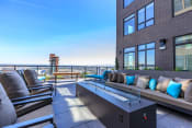 Thumbnail 5 of 24 - an outdoor patio with a firepit and lounge seating with a view of the city at Napoleon Apartments, Tacoma