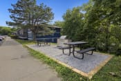 Thumbnail 11 of 14 - a picnic area with benches and a picnic table next to a sidewalk