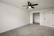Thumbnail 8 of 14 - an empty living room with a ceiling fan and white walls