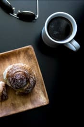 Thumbnail 33 of 33 - a doughnut sitting on top of a wooden cutting board next to a cup of coffee