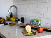 Thumbnail 10 of 33 - a kitchen counter with an apple on a cutting board