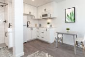 Thumbnail 6 of 12 - a kitchen with white cabinets and a white dining table with two white chairs