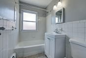 Thumbnail 10 of 16 - a bathroom with white tiled walls and floors and a white bathtub with a shower curtain
