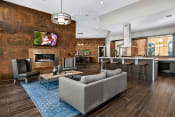 Thumbnail 3 of 26 - First and Main Apartments clubhouse fireplace lounge area and kitchen breakfast bar