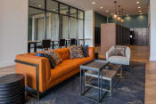 Thumbnail 51 of 75 - seating area with orange couch, white chair, and various sizes of side tables on a gray rug at The Apex at CityPlace, Overland Park