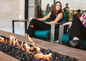 Thumbnail 61 of 75 - two women sitting oudoors in lounge chairs around a fire pit table at The Apex at CityPlace, Overland Park, KS