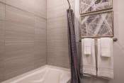 Thumbnail 41 of 75 - a tub with a shower curtain and towels in a bathroom at The Apex at CityPlace, Kansas