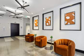 Thumbnail 34 of 50 - a lobby with orange chairs and pictures on the wall
