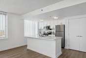 Thumbnail 12 of 50 - a white kitchen with a large island and stainless steel refrigerator
