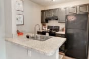 Thumbnail 7 of 29 - a kitchen with granite countertops and black appliances at Hamilton at Kings Place, Columbia, MD