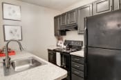 Thumbnail 4 of 29 - a kitchen with black appliances and white granite countertops at Hamilton at Kings Place, Maryland, 21046