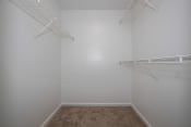 Thumbnail 14 of 22 - a walk in closet in a bedroom with white walls and carpet