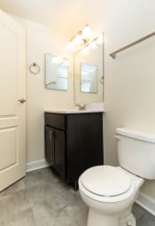 Thumbnail 16 of 39 - a bathroom with a toilet sink and mirror at Seminary Roundtop Apartments, Lutherville, Maryland