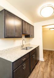 Thumbnail 3 of 39 - a kitchen with dark wood cabinets and a granite counter top at Seminary Roundtop Apartments, Lutherville