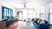 Thumbnail 10 of 28 - a living room with a blue couch and a ceiling fan