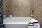 Thumbnail 11 of 28 - a white bath tub in a tiled bathroom