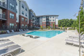 Thumbnail 16 of 18 - Hermitage Apartments - Expansive Pool And Pool Deck, Lounge Chairs, And Maintained Landscaping. Apartments Are In The Background.