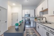 Thumbnail 1 of 18 - a kitchen with white cabinets and gray countertops