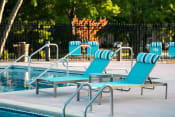 Thumbnail 4 of 26 - a pool with blue chaise lounge chairs and a poolside table