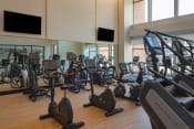 Thumbnail 66 of 75 - indoor gym with rows of elipticals, treadmills, and workout bicycles at The Apex at CityPlace, Kansas, 66210