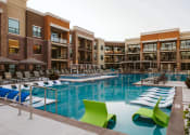 Thumbnail 2 of 75 - The outdoor pool at an apartment home surrounded by chairs at The Apex at CityPlace, Overland Park