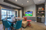 Thumbnail 44 of 78 - a resident clubhouse with a table and chairs and a flat screen tv  at EdgeWater at City Center, Lenexa, KS, 66219