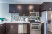 Thumbnail 58 of 78 - a kitchen with dark cabinets and stainless steel appliances  at EdgeWater at City Center, Lenexa, KS
