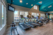 Thumbnail 46 of 78 - a room filled with cardio equipment and a flat screen tv  at EdgeWater at City Center, Lenexa, 66219