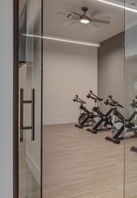 a room with a glass door and a row of exercise bikes in it