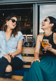 two women sitting on a bench laughing and drinking beer at Cadence, Seattle, WA, 98107