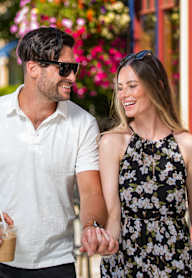A man and a woman are walking down the street holding hands.