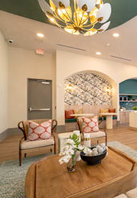 A large room with a chandelier, couches, and a coffee table.