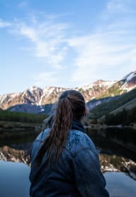 a woman looking out over a lake and mountains