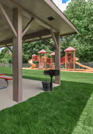 a picnic pavilion with picnic tables in front of a playground