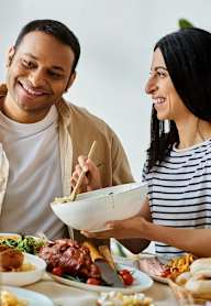 a man and woman sitting at a table with a bowl of food