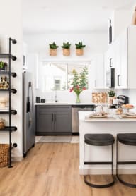 a kitchen with white cabinets and a counter and black stools