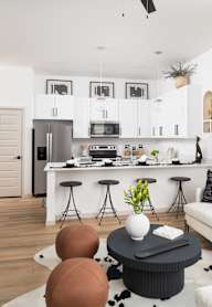 A modern living room with a kitchen in the background.