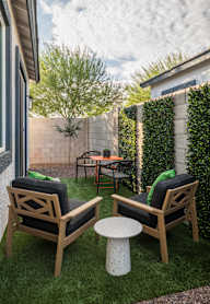 Two chairs and a table are on a lawn.