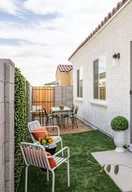 A patio with a table and chairs is surrounded by a wall and a tree.