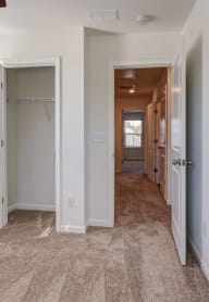 an empty room with a hallway leading to a closet and a window