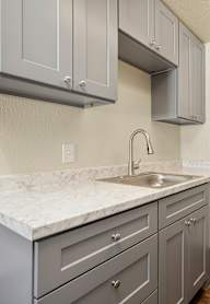 A kitchen with a marble countertop and grey cabinets.
