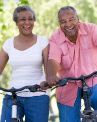 an older couple riding bikes in the park