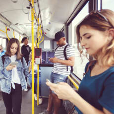 people standing on a bus looking at their cell phones