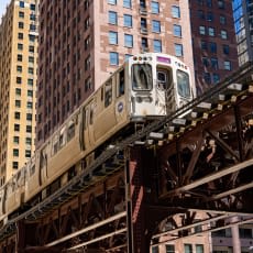 A train is on a bridge in a city.